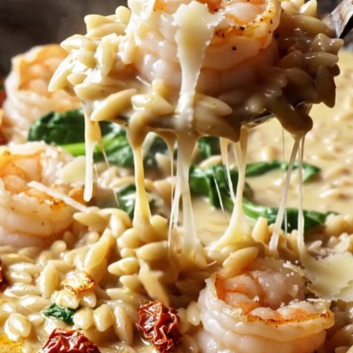 Creamy Tuscan garlic shrimp with orzo and spinach in a skillet, garnished with parmesan