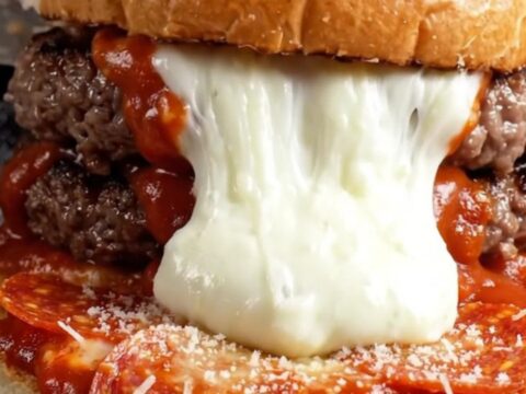 Giant mozzarella stuffed pizza burger on brioche, cut in half showing cheese pull