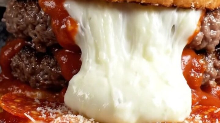 Giant mozzarella stuffed pizza burger on brioche, cut in half showing cheese pull