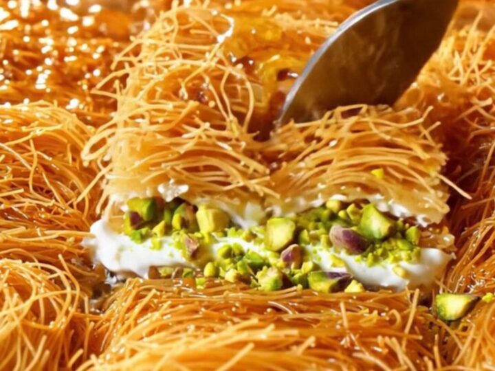 Golden kadayıf baklava with clotted cream and pistachios, drizzled with syrup on a copper tray.