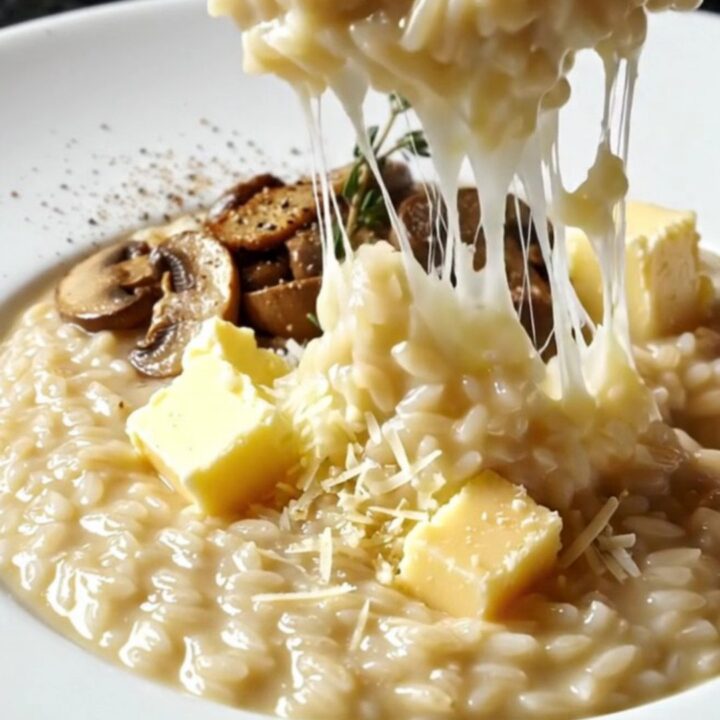 Creamy wild mushroom risotto topped with seared mushrooms and fresh thyme in a pan