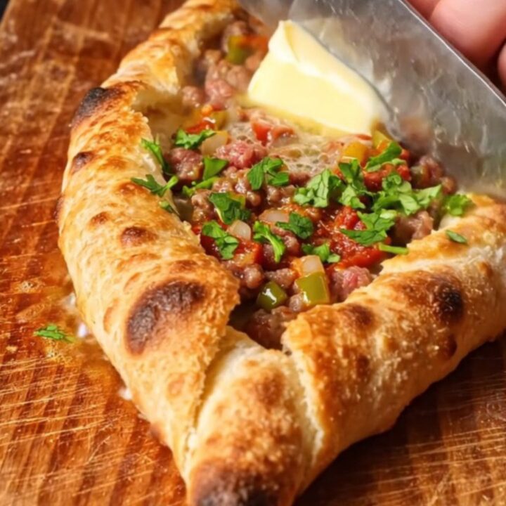 Golden boat-shaped Turkish pide with spiced beef filling and melted butter on top