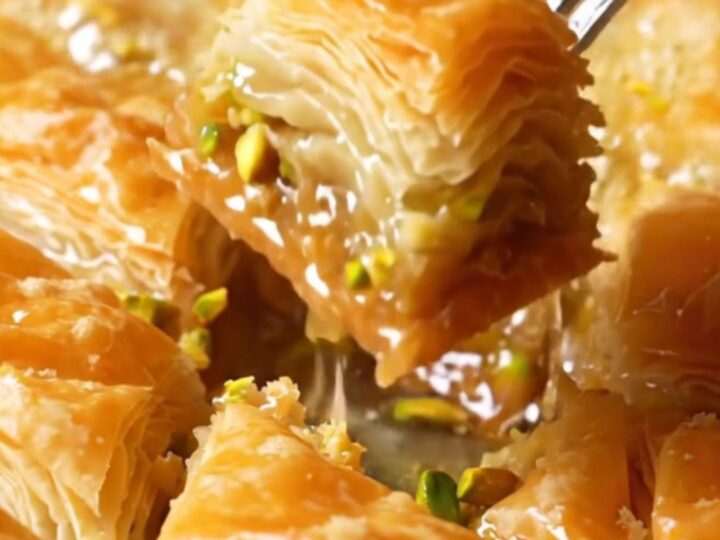 Golden diamond-cut baklava with syrup being poured, showing crispy layers and pistachio filling.