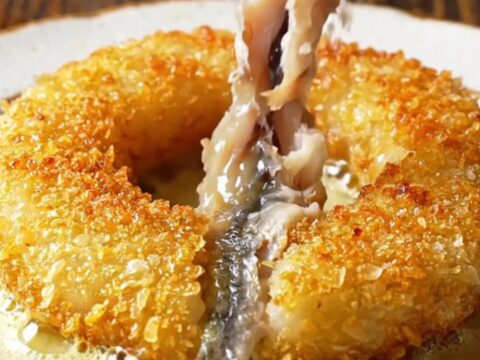 Golden pinwheel of crispy cornmeal-crusted anchovies in a skillet