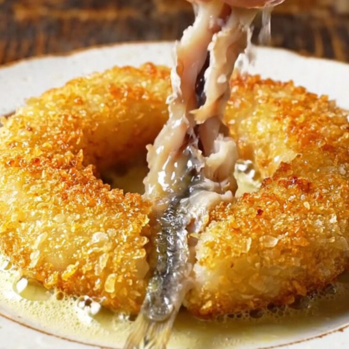 Golden pinwheel of crispy cornmeal-crusted anchovies in a skillet
