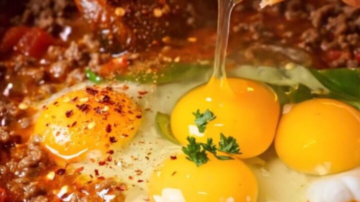 Copper pan of Turkish menemen with ground beef, tomatoes, and soft eggs, crusty bread on the side