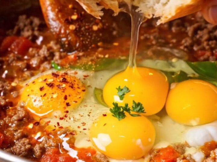 Copper pan of Turkish menemen with ground beef, tomatoes, and soft eggs, crusty bread on the side