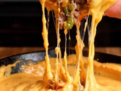 Giant stuffed meatball with molten provolone and peppers, on a cutting board