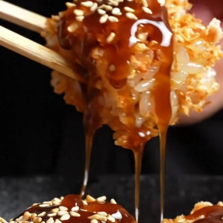 Crispy rice salmon nigiri bites on a dark plate, topped with spicy mayo, jalapeño, and sesame seeds.