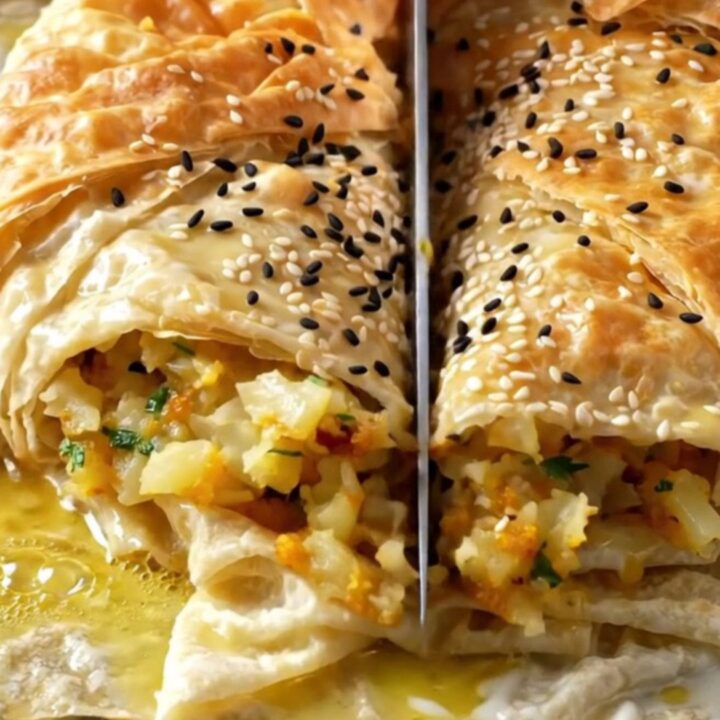 Golden crispy Turkish potato borek in a copper tray, cut into squares