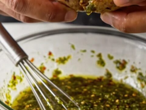 Golden crispy smashed potatoes with green chimichurri sauce on a white plate