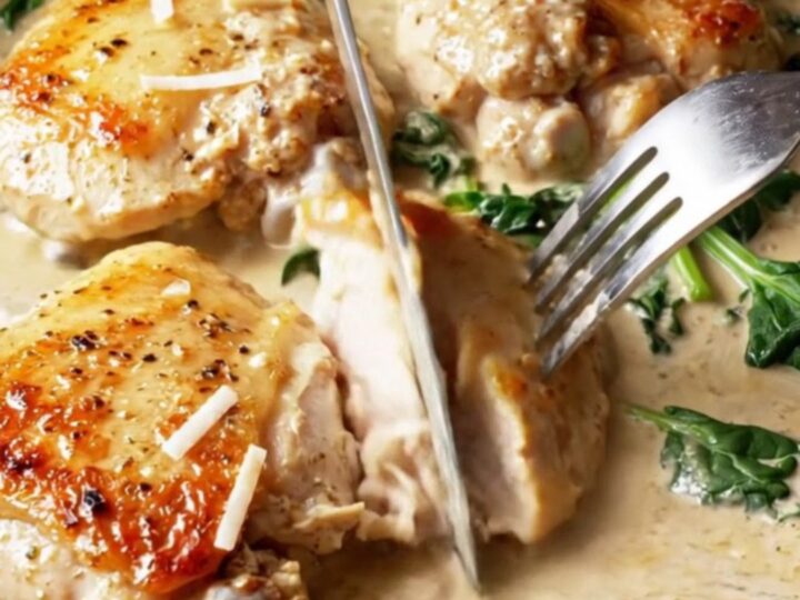 Golden chicken thighs in a creamy Tuscan sauce with sun-dried tomatoes and spinach in a cast iron skillet