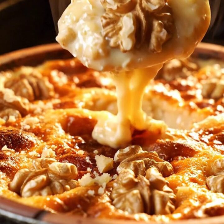 Warm baked tahini halva in a clay dish, caramelized top with crushed walnuts