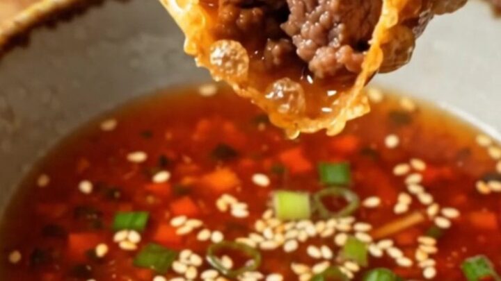 Golden, blistered rice paper dumplings piled on a plate with a small bowl of spicy soy dip.