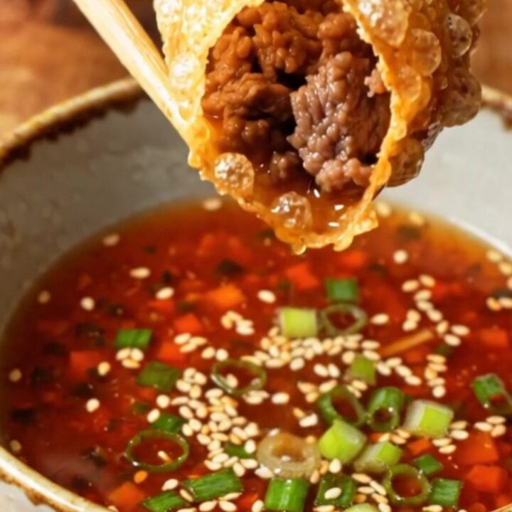 Golden, blistered rice paper dumplings piled on a plate with a small bowl of spicy soy dip.
