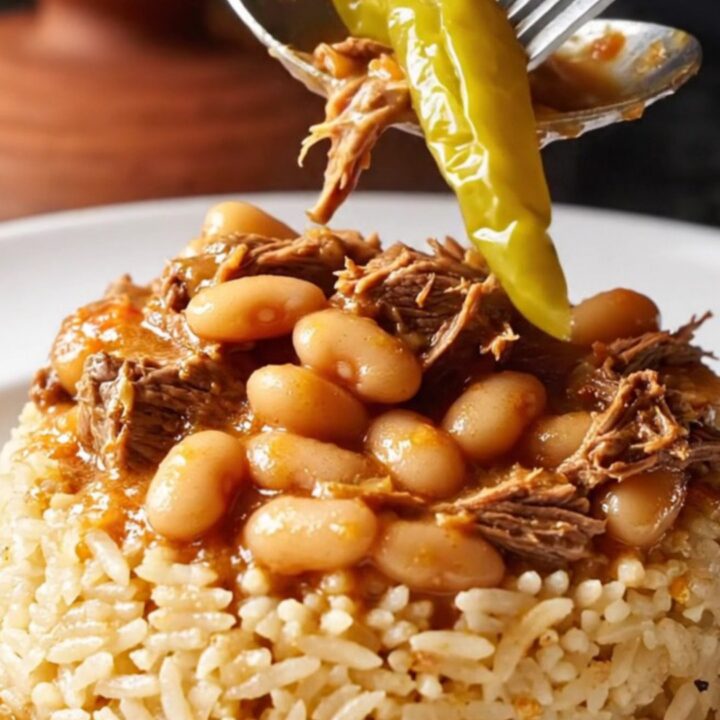A clay pot of Turkish white beans and beef stew, thick with tomato-pepper gravy, being ladled over rice pilaf.