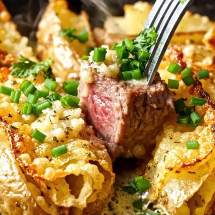 Seared garlic butter steak cubes and crispy accordion potatoes in a cast iron skillet