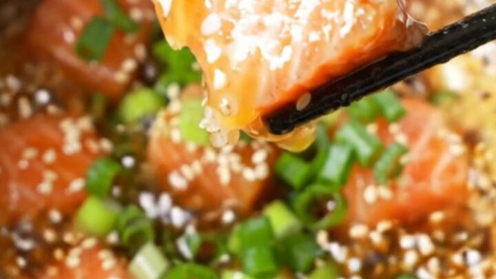 Crispy air-fried salmon cubes coated in sticky honey garlic glaze, sprinkled with sesame seeds and scallions, in a bowl