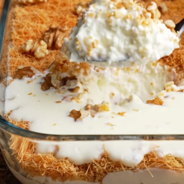 A glass dish of Turkish Kadayıflı Muhallebi with golden crispy kadayıf and walnuts on top, creamy pudding visible beneath.
