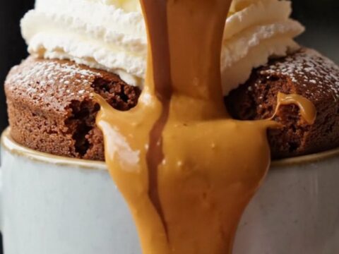 Molten chocolate peanut butter lava mug cake with powdered sugar and whipped cream