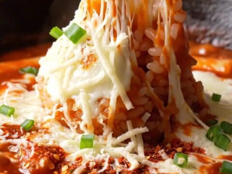 Skillet of Korean cheesy fire tteokbokki with melted mozzarella and scallions