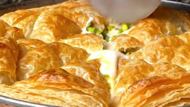 Golden, blistered katmer pastry on a copper pan, with pistachios visible