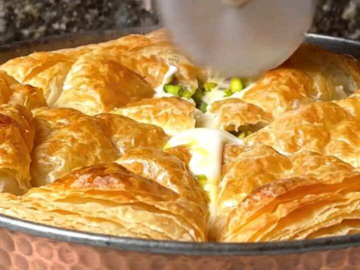 Golden, blistered katmer pastry on a copper pan, with pistachios visible
