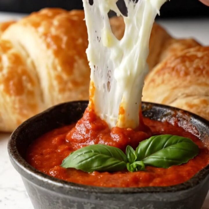 Golden pull-apart crescent ring with melted cheese stretch on a baking sheet
