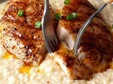 Blackened chicken slices over creamy white cheddar grits with spiced butter drizzle and chives