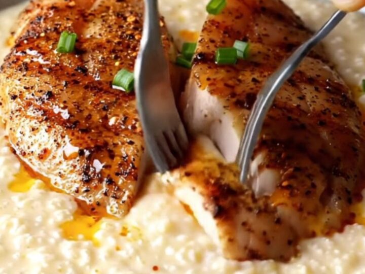 Blackened chicken slices over creamy white cheddar grits with spiced butter drizzle and chives