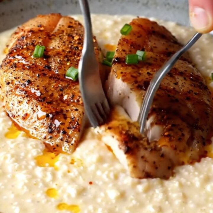 Blackened chicken slices over creamy white cheddar grits with spiced butter drizzle and chives
