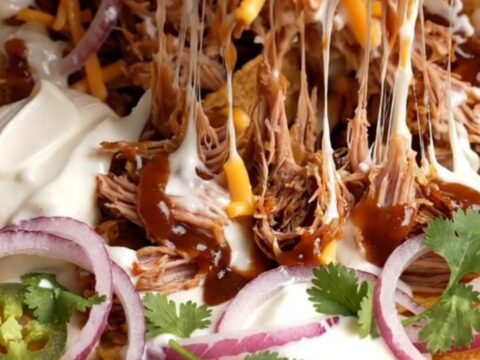 Loaded skillet pulled pork nachos with melted cheese and jalapeños