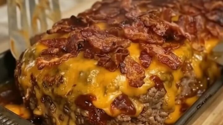 A thick, juicy slice of bacon cheeseburger meatloaf with melted cheddar and crispy bacon on top.