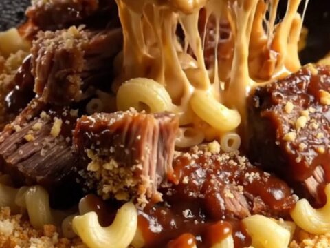 Bubbling cast iron skillet with smoked brisket mac and cheese, topped with golden panko and barbecue drizzle