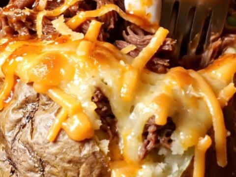 Birria stuffed baked potato with melted cheese and consommé