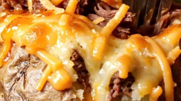 Birria stuffed baked potato with melted cheese and consommé