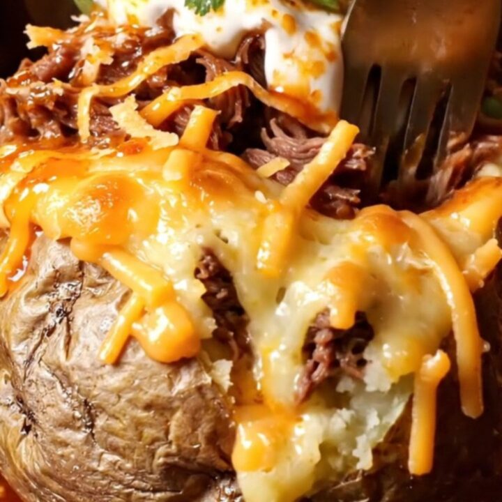 Birria stuffed baked potato with melted cheese and consommé