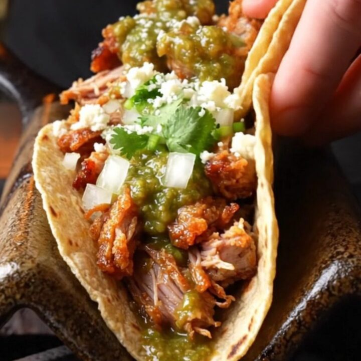 Crispy pork carnitas tacos with salsa verde, onions, cilantro, and lime on charred corn tortillas