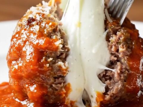 Giant meatball cut open showing molten buffalo mozzarella pull with marinara sauce
