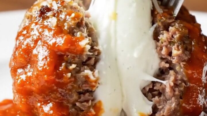 Giant meatball cut open showing molten buffalo mozzarella pull with marinara sauce