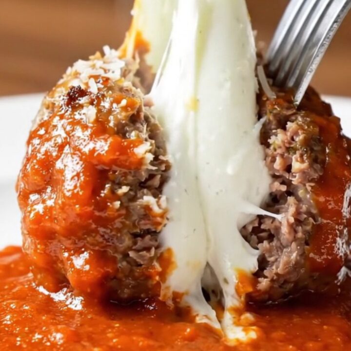 Giant meatball cut open showing molten buffalo mozzarella pull with marinara sauce