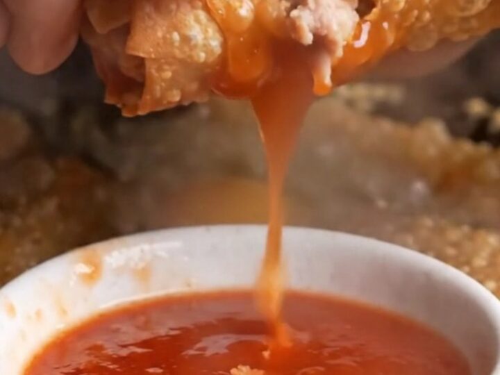 Crispy rice paper egg rolls with blistered golden crust, served with sweet plum sauce in a small bowl.