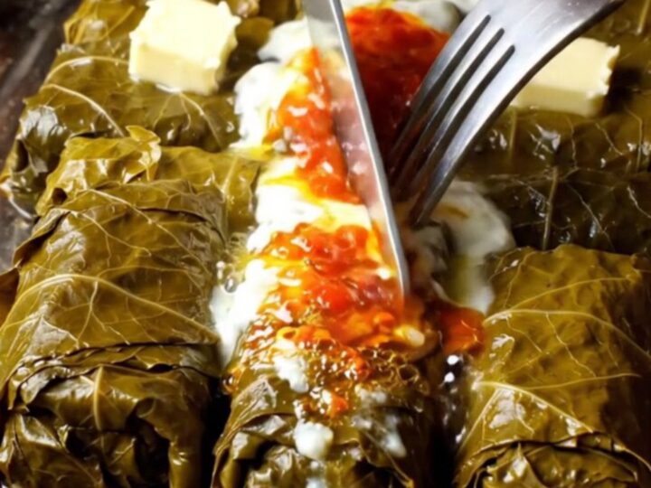A pot of Turkish stuffed grape leaves topped with garlic yogurt and red pepper butter