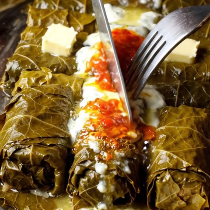 A pot of Turkish stuffed grape leaves topped with garlic yogurt and red pepper butter