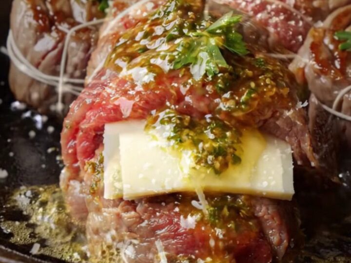 Chimichurri butter flank steak pinwheels seared in a cast-iron skillet, with melted cheese and herb sauce