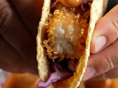 Golden beer-battered fish tacos with purple cabbage slaw and chipotle crema on corn tortillas