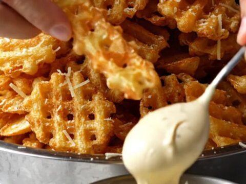 A pile of golden waffle fries tossed with truffle oil, topped with grated Parmesan and parsley