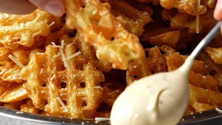 A pile of golden waffle fries tossed with truffle oil, topped with grated Parmesan and parsley