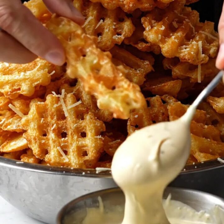A pile of golden waffle fries tossed with truffle oil, topped with grated Parmesan and parsley