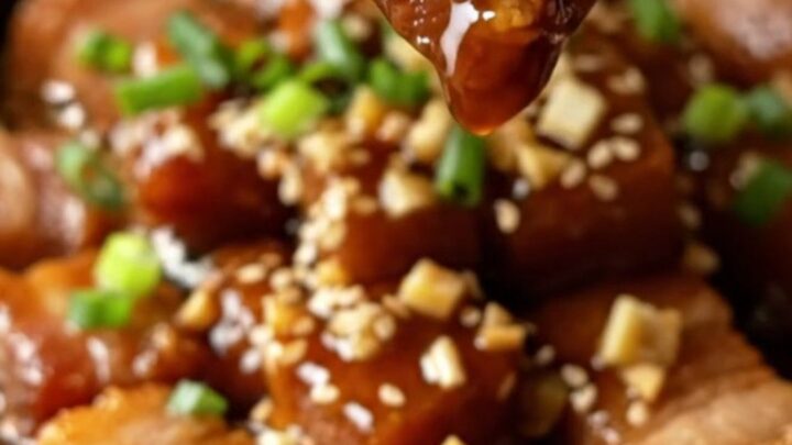 Sticky honey soy garlic pork belly bites with sesame and scallions in a skillet